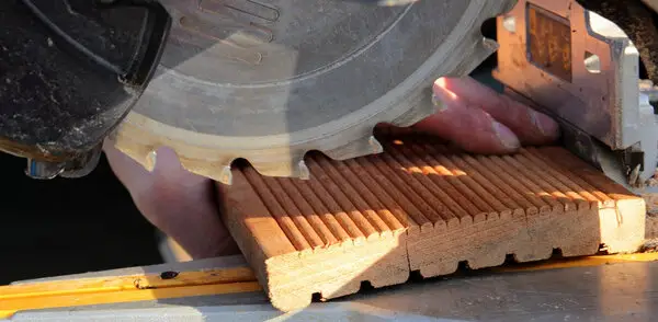 A finish carpenter in McKinney using a circular saw to cut a piece of wooden trim.