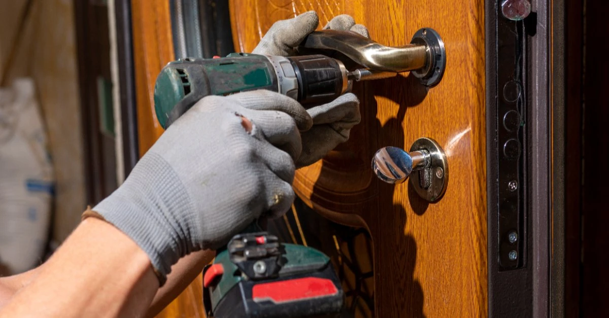 A handyman using a drill to provide exterior door repair services for the front door of a home in Collinsville, IL.