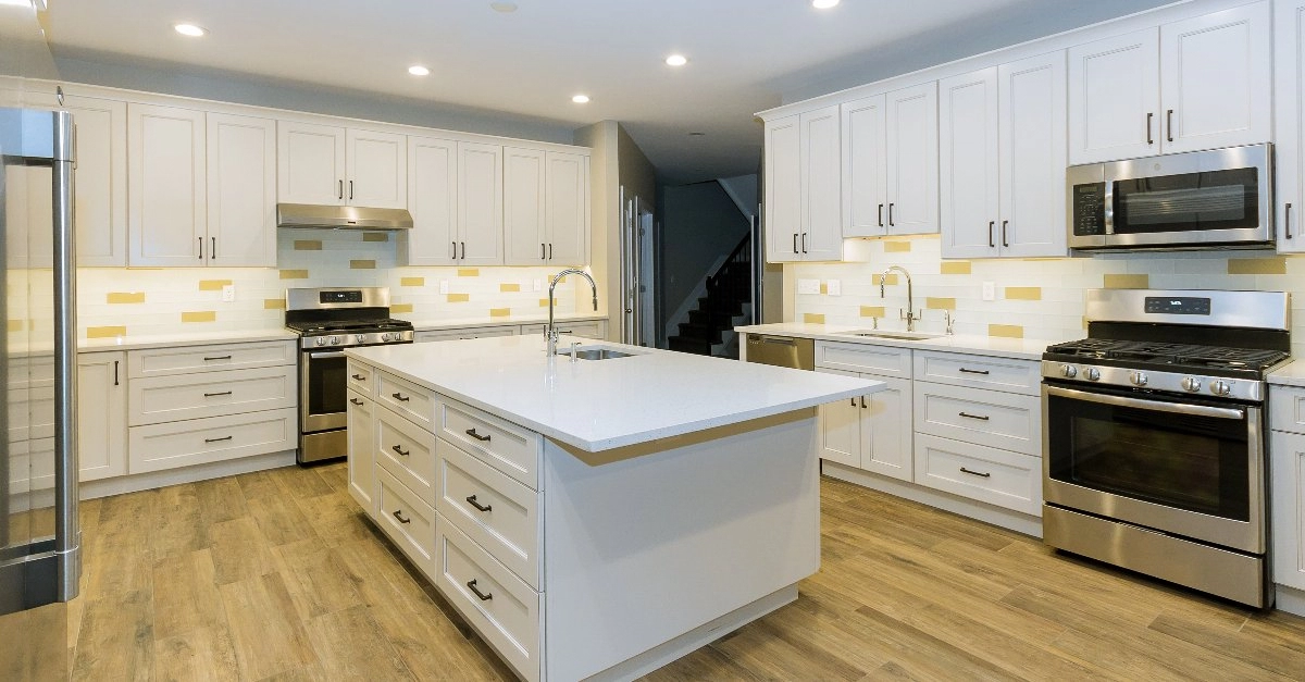 A completed Walpole kitchen remodel for a modern kitchen with white cabinets, an island, a glass backsplash, and white countertops.