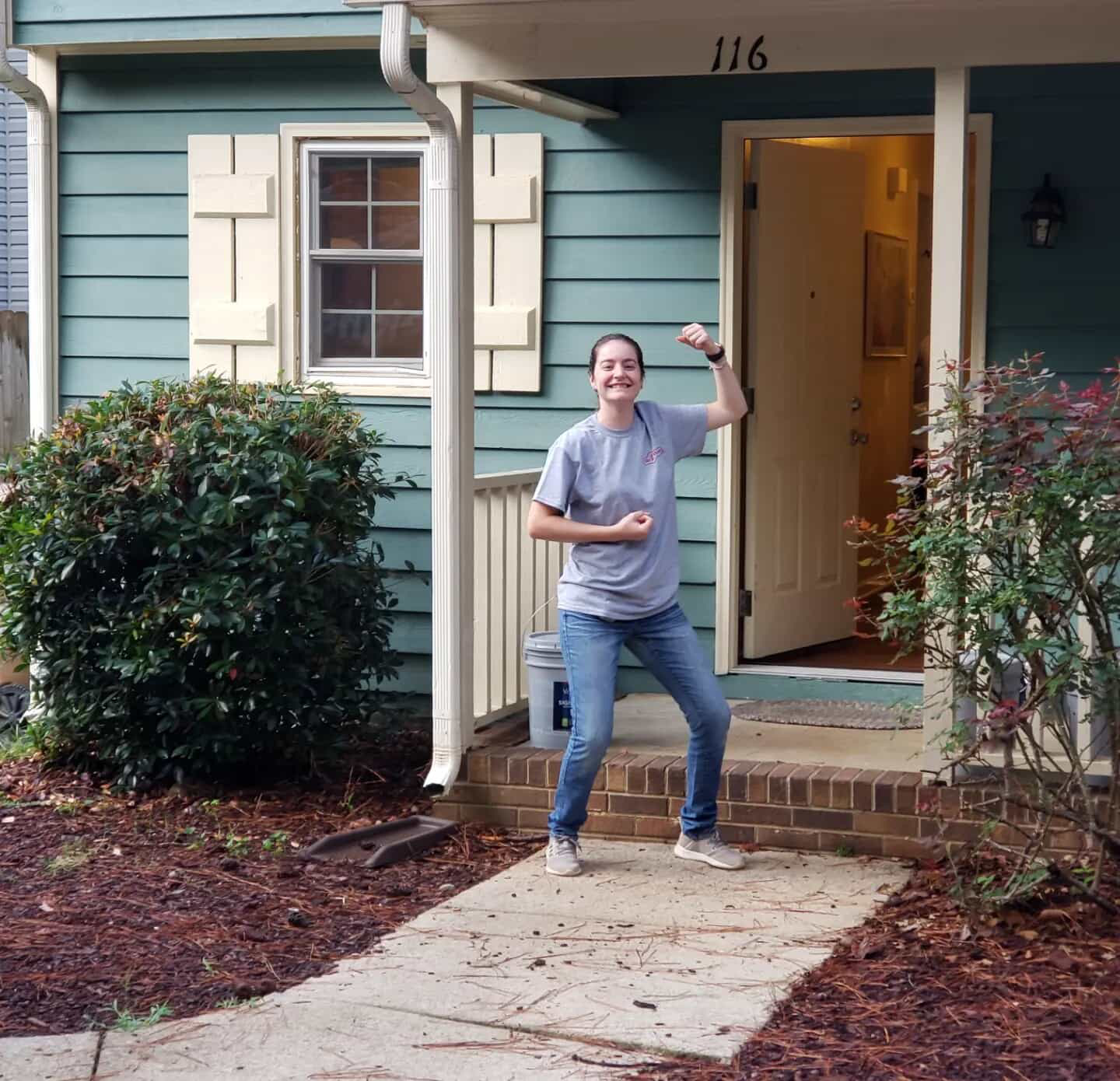 Person flexing arm in front of a home.