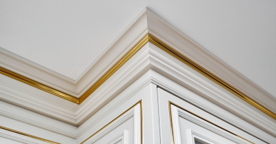 White, elaborate crown molding with a gold trim running along the ceiling joint in a home that has just received service for trim installation in Wichita, KS.