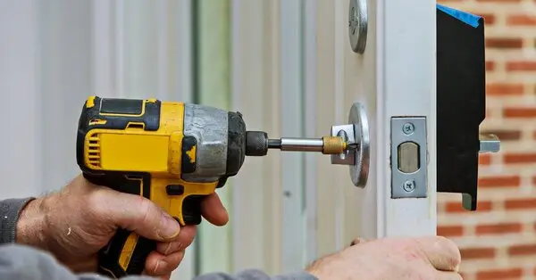 A handyman using a drill for door replacement in Wichita, KS