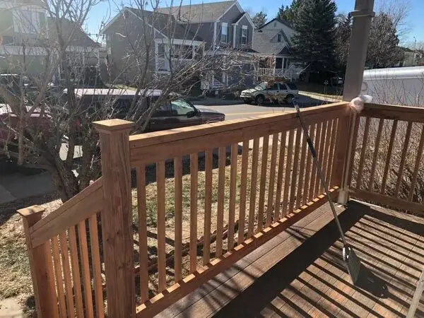 A broom leaning on the railing of a wooden deck that has been swept clean after receiving deck repair services from Mr. Handyman.