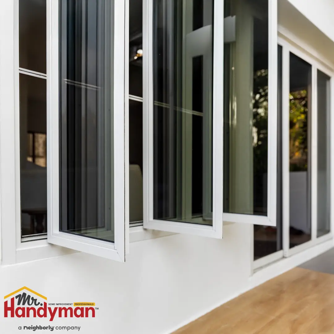 White-framed glass windows in a residential setting, some panels tilted open above a wooden floor.