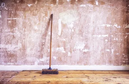 broom leaning against textured wall