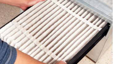 Handyman replacing dirty furnace air filter during winter home maintenance in Bethlehem Pennsylvania.