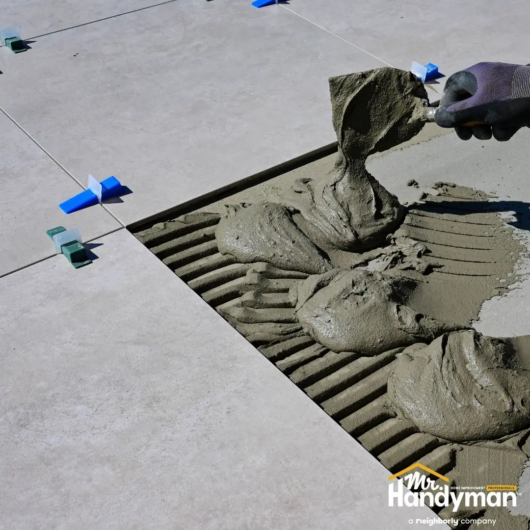 Tile flooring installation with mortar being spread under tiles.