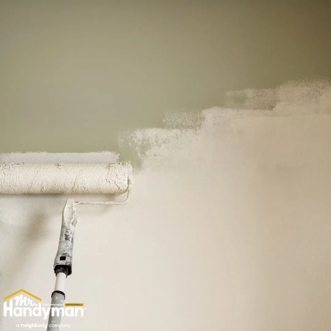 Paint roller applying fresh paint to an interior wall.