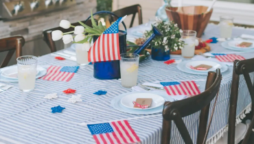 Table setting with patriotic red, white, and blue decorations, including an American flag centerpiece.
