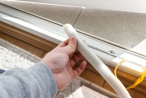 man doing DIY and installing weatherstripping for attic door insulation.