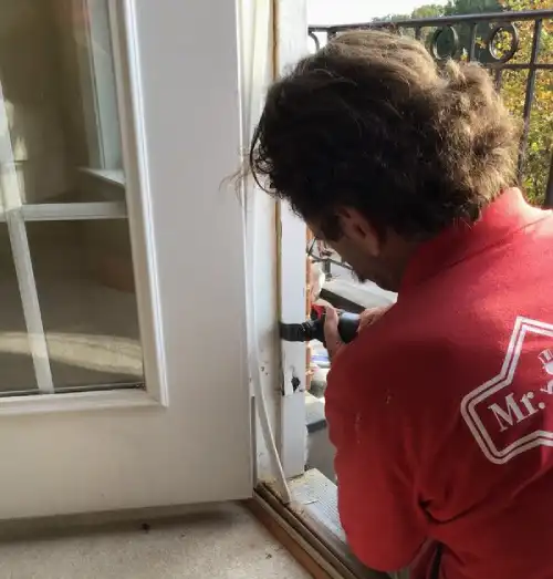 Mr. Handyman technician repairing door hinge.