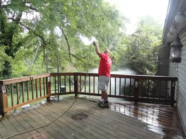 Mr. Handyman technician power washing wood deck.