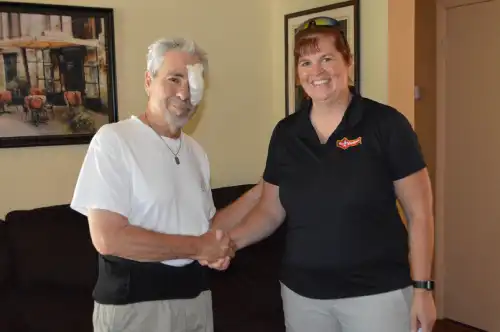 Mr. Handyman owner Jo McCabe shaking hands with veteran in living room.