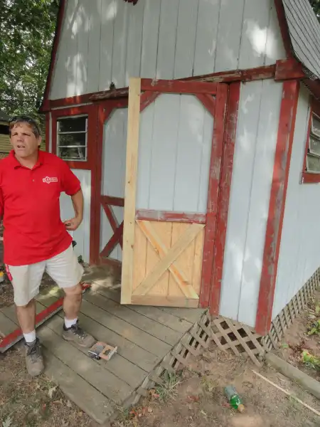 Mr. Handyman technician standing next to a wood shed.