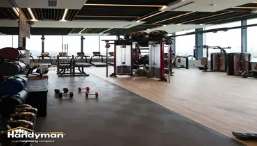Mr. Handyman technician professionally installing large gym mirrors on a fitness facility wall in Nashville.