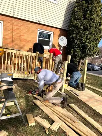 Mr. Handyman technicians outside of veteran's home building wheelchair ramp.