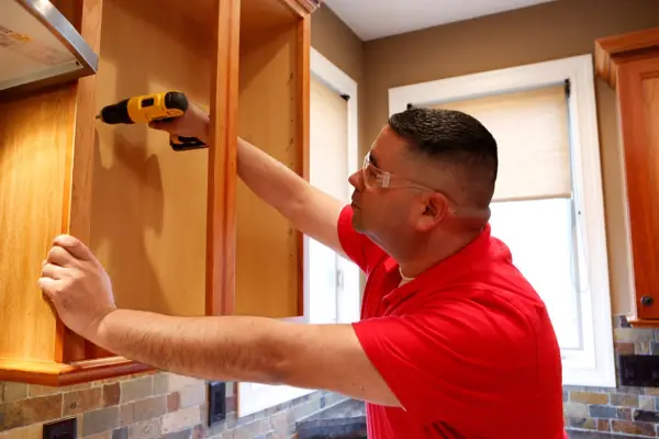 Mr. Handyman installing new cabinets during kitchen remodel in Keller home.