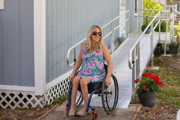 A woman in a wheelchair at the bottom of an aluminum elevation ramp.