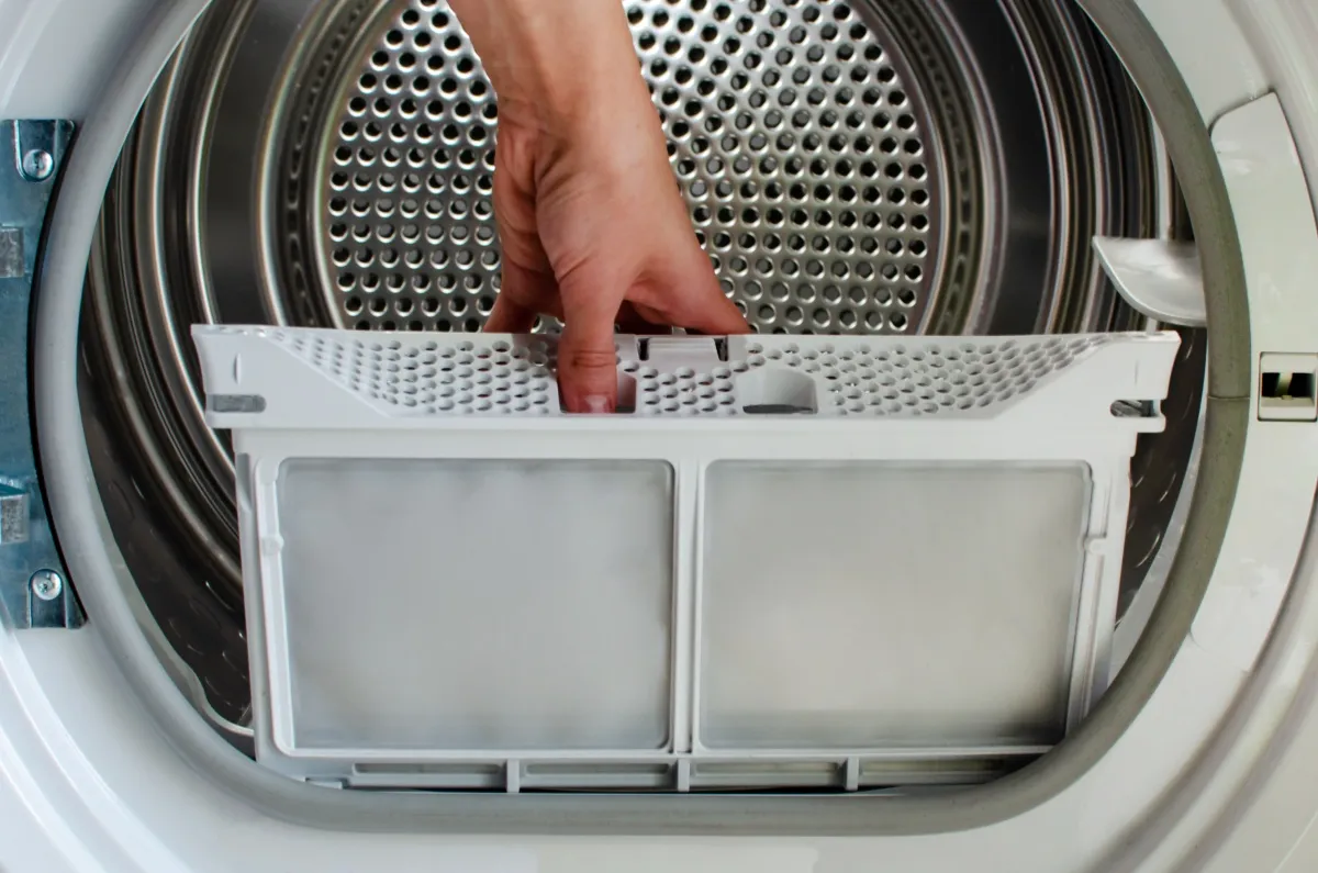 Dallas handyman removing lint trap during dryer cleaning.